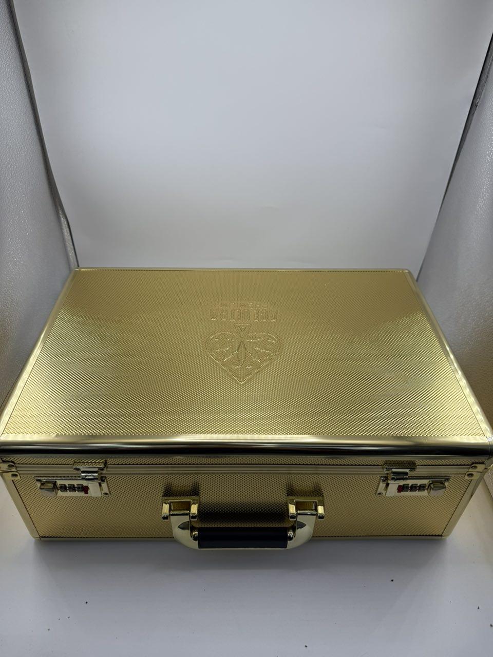 Gold metallic, textured briefcase with two combination locks and a black-handled latch on a white surface. Intended for secure storage or transport of valuables.",